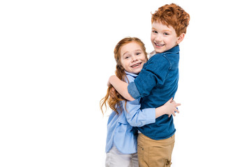 beautiful redhead brother and sister hugging and smiling at camera isolated on white