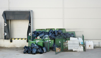Green  garbage containers  with black plastic bags near the large food city  market shop.