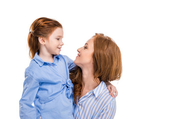 beautiful redhead mother and daughter smiling each other isolated on white