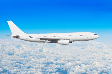 Fototapeta premium White passenger wide-body aircraft flies travel, trip at the flight level cumulus clouds, above against the blue sky.