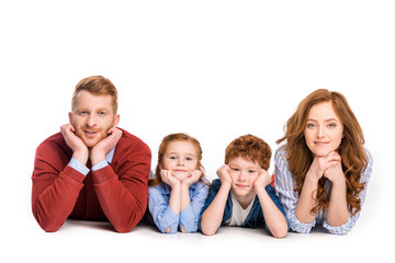 happy redhead family lying together and smiling at camera isolated on white