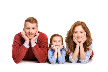 happy redhead family with one child lying together and smiling at camera isolated on white