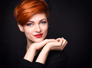 Portrait of a beautiful young red-haired woman with short hair on a dark background