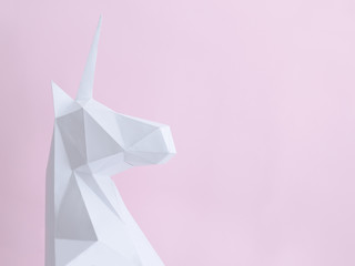 White paper unicorn on a pink background. Space for text