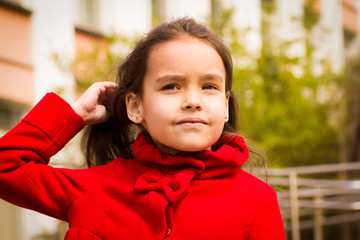 cute smiling girl in a red coat and tucks her hair