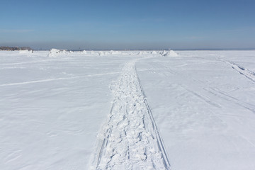 Trace of a snowmobile on a snowy surface of frozen reservoir, Siberia,  Ob Reservoir, Russia