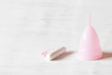 Pink fame cup and white tampon on white vintage background. Copy space, selective focus.