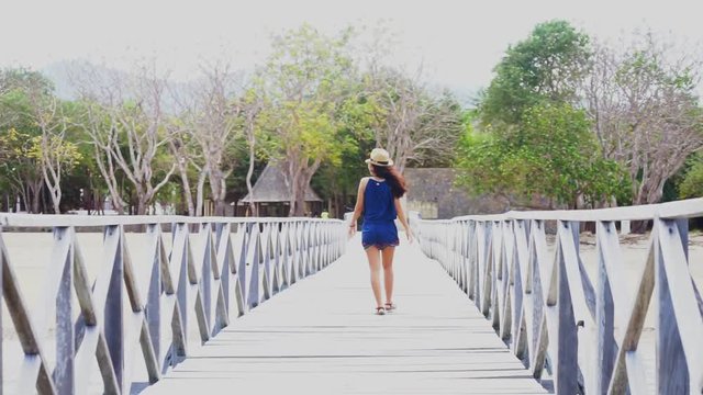 Back view of a young woman walking on the wooden jetty while enjoying holiday at Komodo Island near Bali, Indonesia