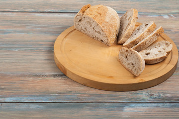 Many mixed breads and rolls of baked bread on wooden table background.