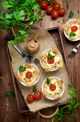 Ramekins with tasty chicken and bacon quiche on wooden board