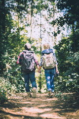 Naklejka na ściany i meble Young couple walking with backpacks in forest. Adventure hikes, Enjoy holidays together,
