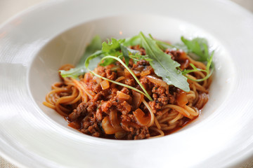 spaghetti Bolognese with minced beef and tomato sauce garnished with parmesan cheese and basil , Italian food