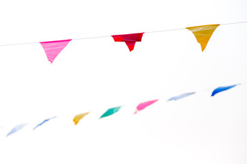 Colorful festive bunting flags against a blue sky and clouds background