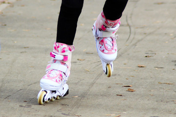 Women's feet on roller skates on the road in the park.