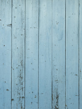 Background of barn wood wall with distressed, peeling blue paint 