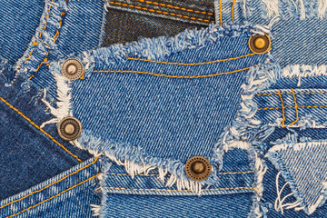 denim buttons on ripped denim patch and destroyed torn blue scraps. Denim double seam jeans fashion background