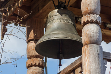 Obraz premium Closeup big bell in wooden bell tower on a slope near holy spring Gremyachiy Klyuch in Svyatogorye, Russia, Moscow region, Sergiev Posad district, village Vzglyadnevo