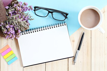 Business, planning, spring or summer concept : Top view or flat lay of open notebook paper, bouquet of dried wild flowers and coffee cup on desk table with copy space ready for adding or mock up