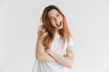 Cheerful woman in t-shirt with crossed arms winks her eye