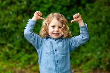 Happy small child with long blond hair and saying OK