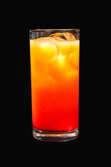 A multicolored, two-layered opaque cocktail in a tall glass with ice cubes, the taste of tomato, pineapple, and orange. Side view Isolated black background. Drink for the menu restaurant, bar, cafe