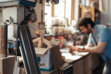 Woodworker using a tablet in his workshop full of tools