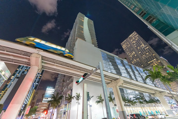 Streets of Downtown Miami at night with moving metrorail train, Florida