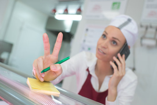 Worker taking telephone order, making hand gesture for quantity