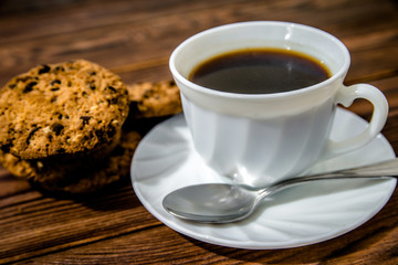 A cup of hot coffee stands on a wooden table 