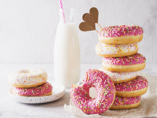 Stack of pink and white donats with bottle of milk over white background