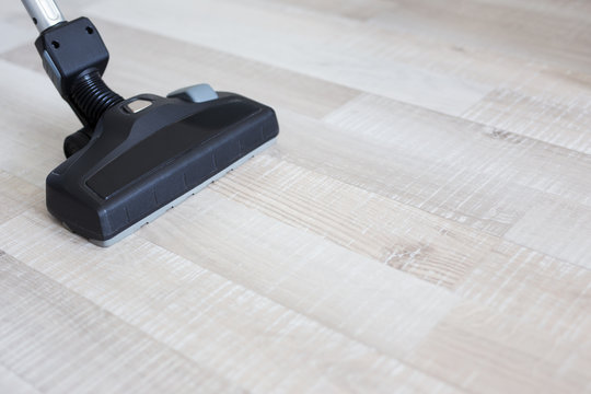 close up of modern vacuum cleaner over wooden parquet floor