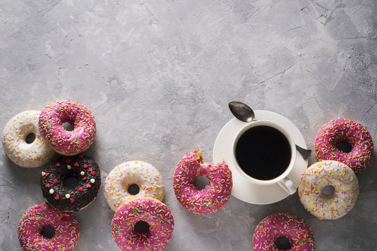 Sone pink and white donuts with cup of coffee over grey stone texture