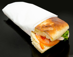 sandwich with ham and cheese wrapped in napkin