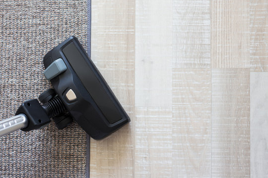 modern vacuum cleaner over carpet and wooden parquet floor