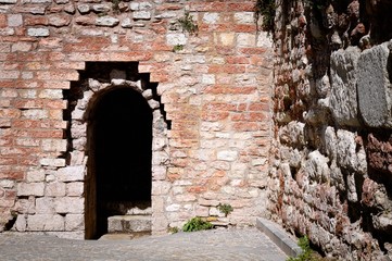 Fototapeta na wymiar Entrance of a Castle - Round arch and brick walls (Spello, Umbria, Italy)