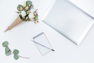 Top view of white office desk table with laptop, notebook, flower composition. Copy space, flat lay.