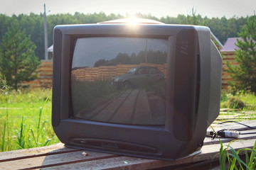 Old TV on the boards under the sky with the reflection of an old car of the 90s. Back to the Future. Back in the 90's.
