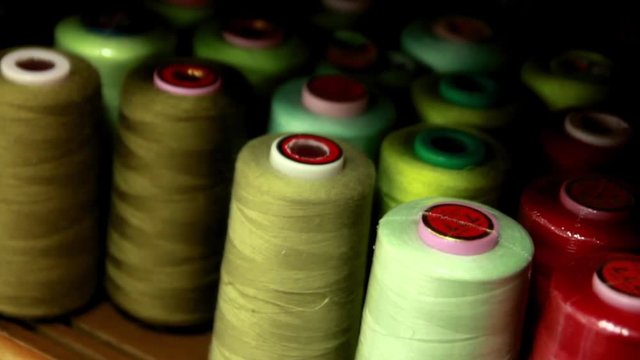 Plastic spools of high quality cotton multicolor sewing thread, close-up. All-purpose thread spools on a sewing machine spindle. 
