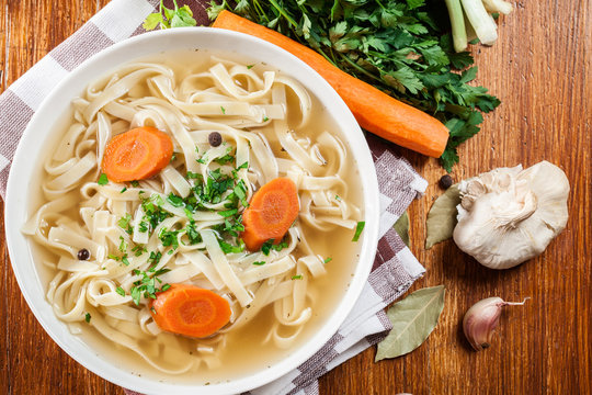 Tasty meat broth with noodles, carror and parsley