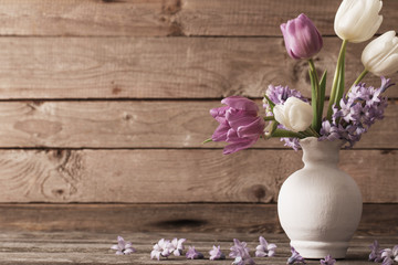 spring flowers in vase on old wooden background