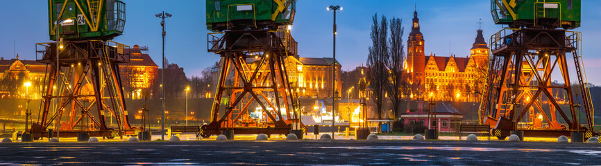 Historical harbor cranes on riverside boulevards in the evening, after a spring downpour