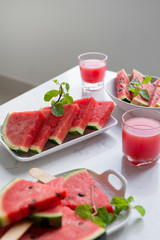 Fresh red smoothie in a glass with sliced pieces of watermelon on table.