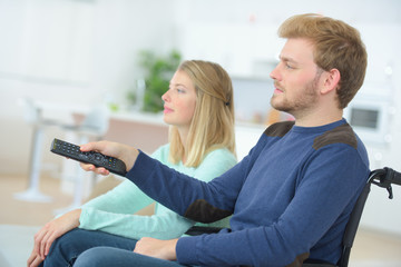 handicapped man using remote control while watching tv