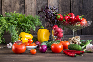Onions, peppers, dill, tomatoes, cucumbers, radishes, dill, rucola and mushrooms on a wooden dark background
