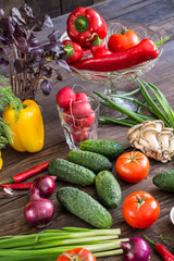 Onions, peppers, dill, tomatoes, cucumbers, radishes, dill, rucola and mushrooms on a wooden dark background