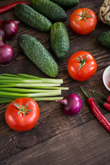 Onions, peppers, dill, tomatoes, cucumbers, radishes, dill, rucola and mushrooms on a wooden dark background