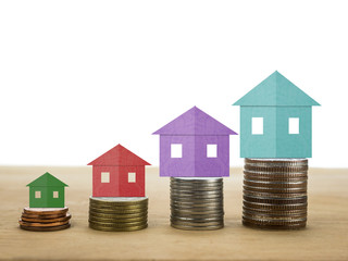 coins stack and home colored paper on wooden white background