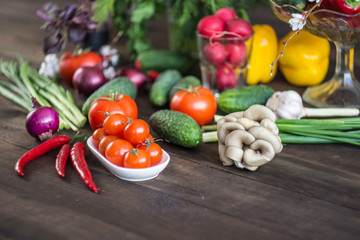 Onions, peppers, dill, tomatoes, cucumbers, radishes, dill, rucola and mushrooms on a wooden dark background