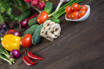 Onions, peppers, dill, tomatoes, cucumbers, radishes, dill, rucola and mushrooms on a wooden dark background