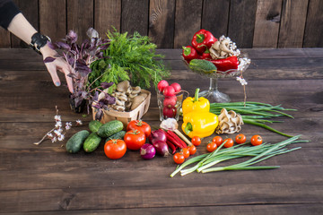 Onions, peppers, dill, tomatoes, cucumbers, radishes, dill, rucola and mushrooms on a wooden dark background